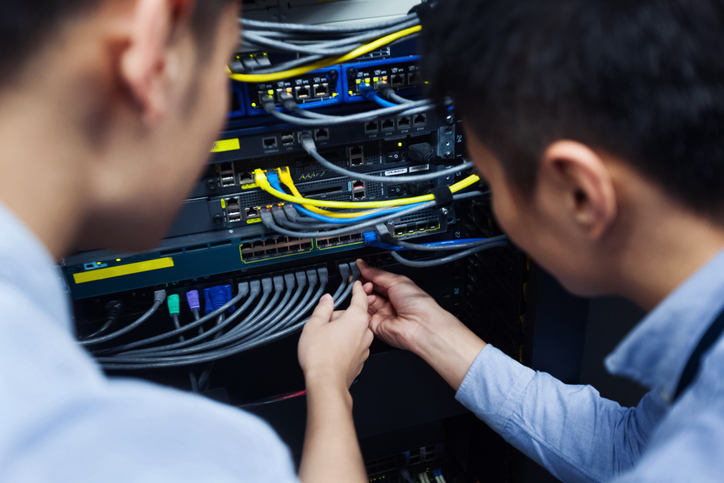 Young IT engineer inspecting network cable